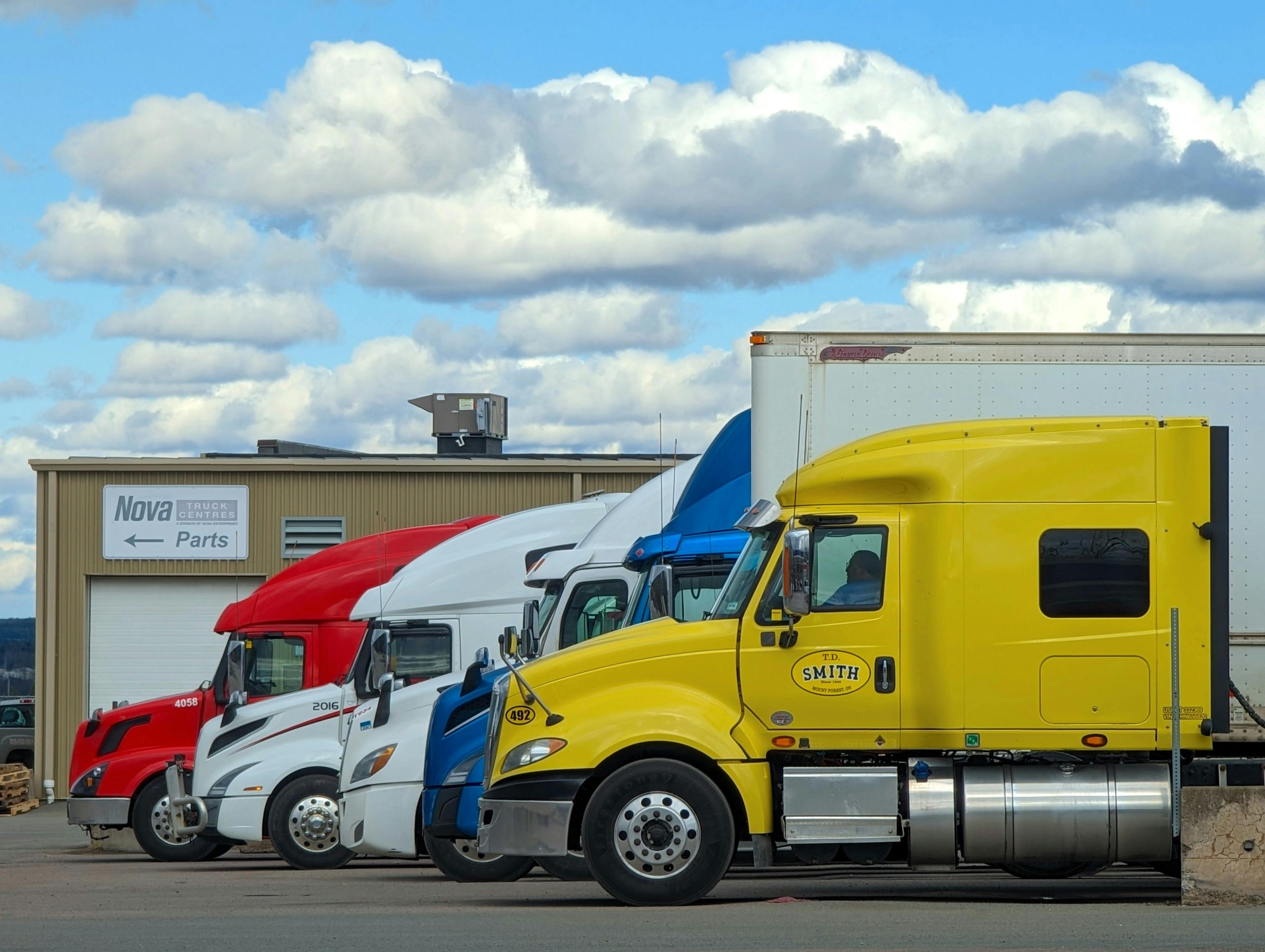 A vibrant lineup of semi trucks parked outside a Nova Truck Center in Truro, NS, Canada.